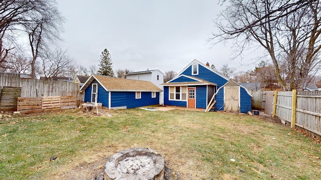 rear view of property with a shed, an outdoor fire pit, and a lawn