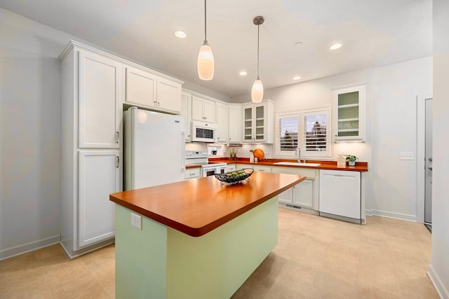 kitchen with sink, wood counters, pendant lighting, white appliances, and white cabinets