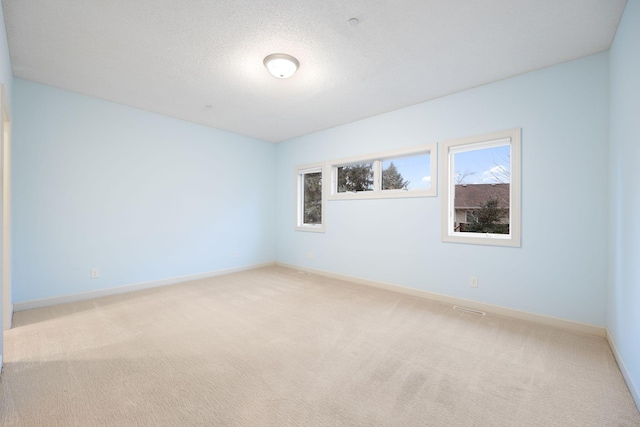 empty room with light carpet and a textured ceiling