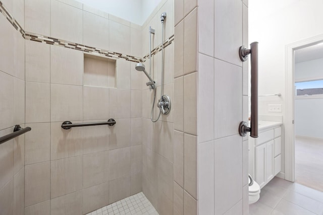 bathroom with toilet, a tile shower, and tile patterned floors