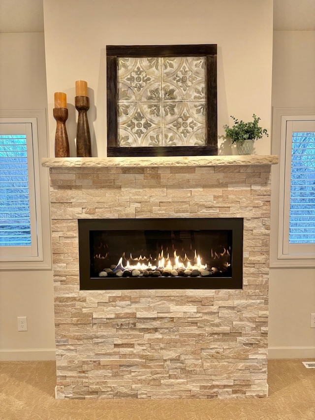 room details with a stone fireplace, carpet, and baseboards