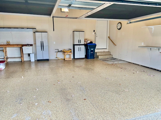 garage with a sink, a garage door opener, and freestanding refrigerator