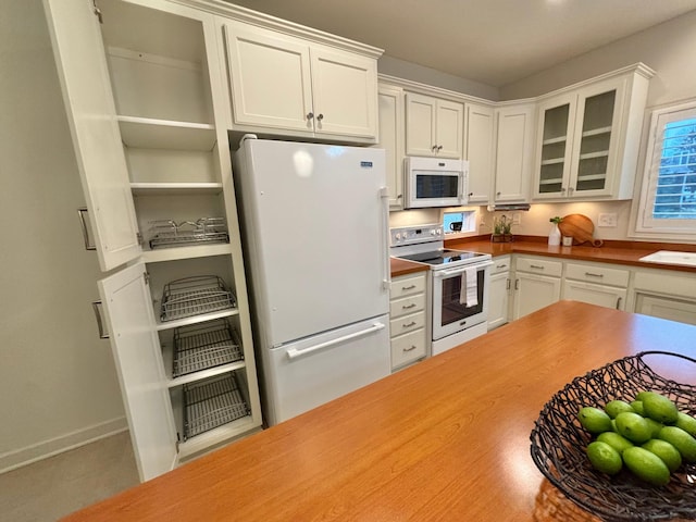 kitchen with white appliances, white cabinets, glass insert cabinets, and baseboards