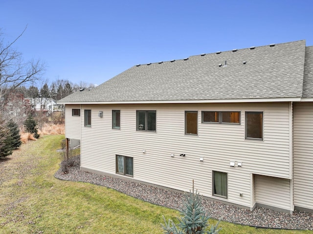 rear view of house with a yard and a shingled roof