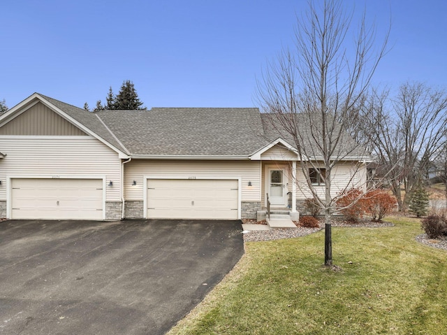 view of front of house featuring a front yard, stone siding, roof with shingles, and aphalt driveway