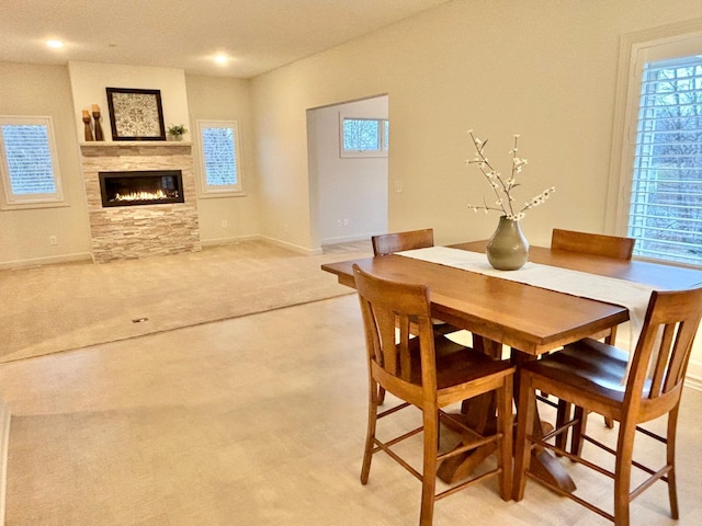 dining space with a stone fireplace, baseboards, and a wealth of natural light