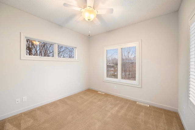 empty room with light colored carpet, baseboards, ceiling fan, and visible vents