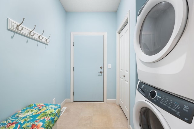 washroom featuring baseboards, laundry area, stacked washer and dryer, and visible vents