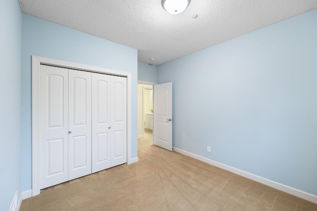 unfurnished bedroom with baseboards, a closet, a textured ceiling, and light colored carpet