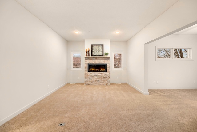 unfurnished living room featuring light colored carpet, recessed lighting, baseboards, and a stone fireplace