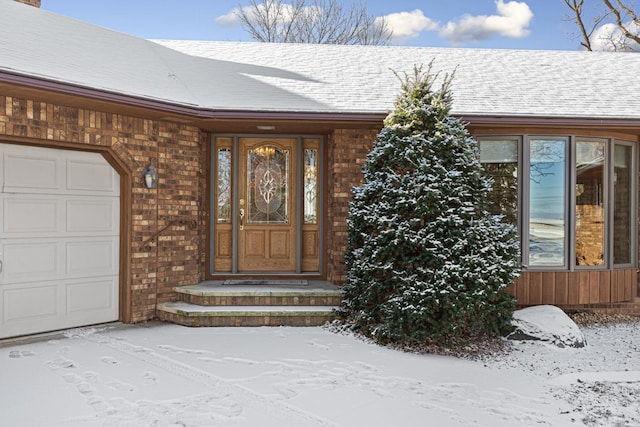 snow covered property entrance with a garage