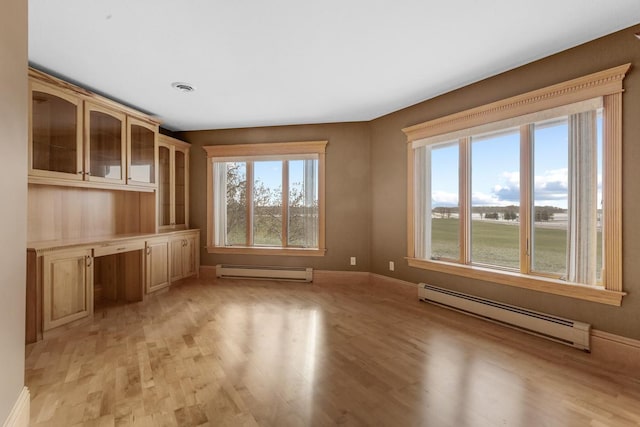 interior space featuring a healthy amount of sunlight, built in desk, and a baseboard heating unit