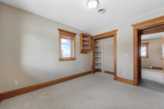 unfurnished bedroom with baseboard heating, multiple windows, light carpet, and a closet