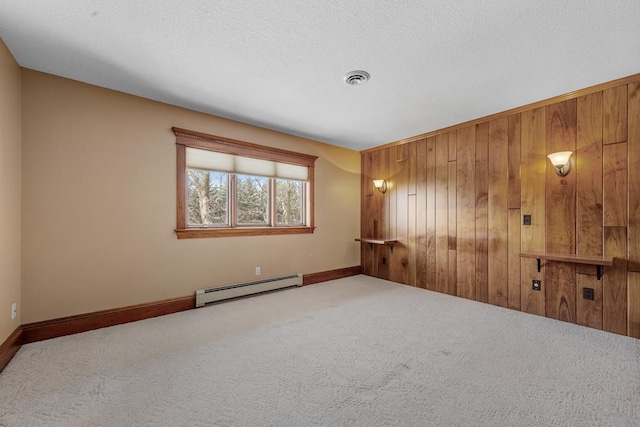 empty room with baseboard heating, wooden walls, carpet floors, and a textured ceiling