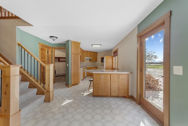 kitchen featuring a kitchen breakfast bar, kitchen peninsula, and light colored carpet