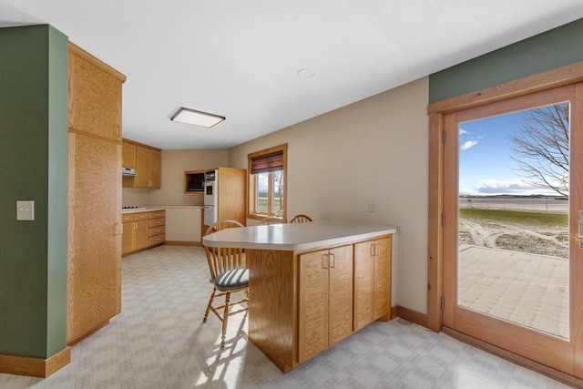 kitchen featuring kitchen peninsula, a kitchen bar, white appliances, and extractor fan