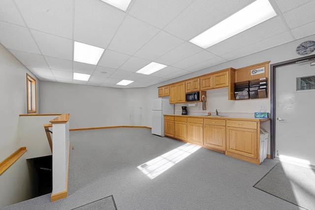 kitchen featuring black microwave, sink, white fridge, a paneled ceiling, and light carpet