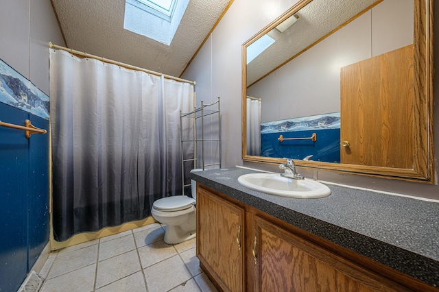 bathroom featuring toilet, tile patterned floors, lofted ceiling with skylight, and vanity