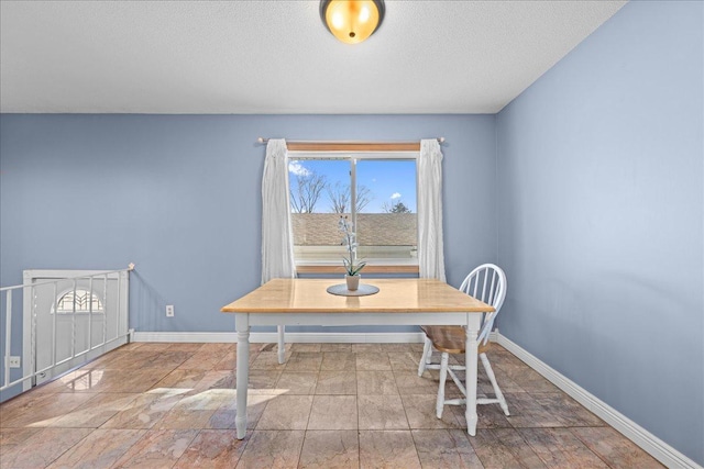 dining space featuring a textured ceiling and baseboards