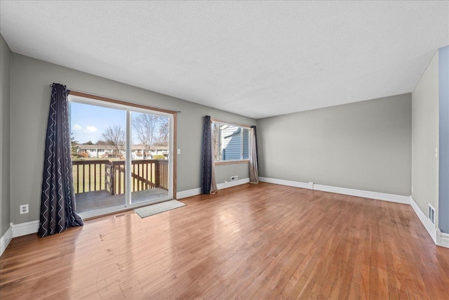 unfurnished room featuring wood finished floors, a textured ceiling, and baseboards