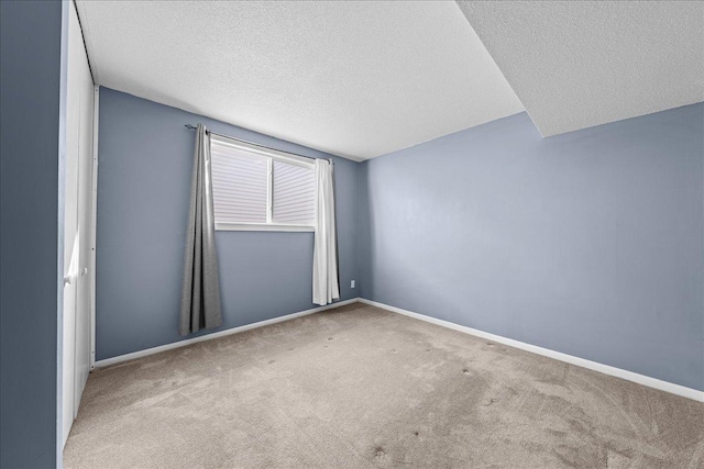 empty room featuring baseboards, carpet flooring, and a textured ceiling