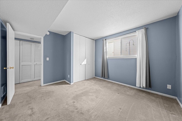 unfurnished bedroom with carpet floors, a textured ceiling, and baseboards