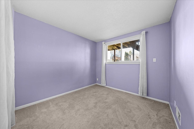 spare room featuring baseboards, a textured ceiling, visible vents, and carpet