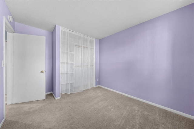 unfurnished bedroom with carpet floors, a textured ceiling, and baseboards