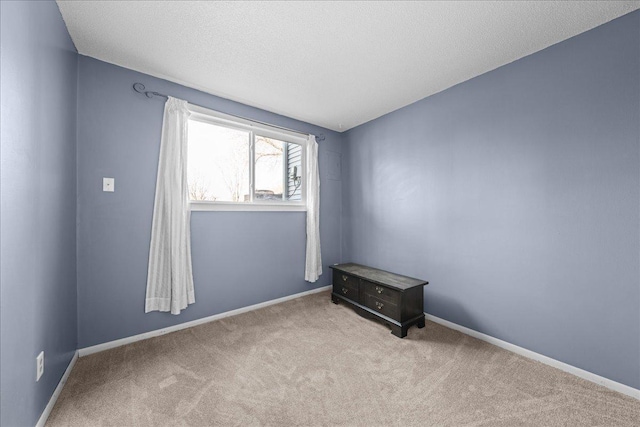 carpeted empty room with baseboards and a textured ceiling