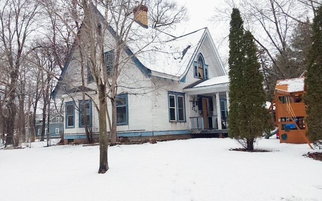 view of front of property featuring a playground, a porch, and a chimney