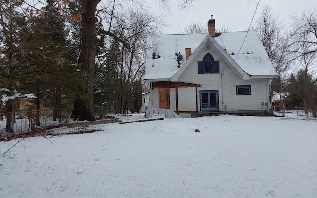 snow covered back of property with a chimney