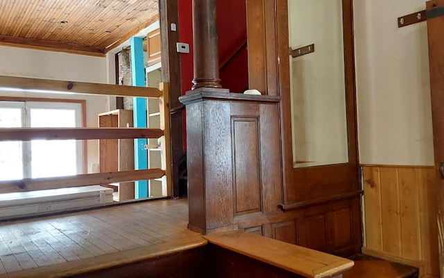 interior space featuring a wainscoted wall, wooden walls, wood ceiling, and wood finished floors
