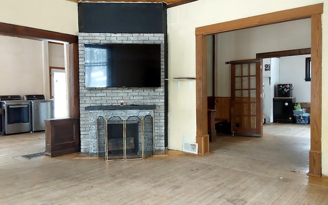 living area featuring washer and dryer, wood finished floors, and a brick fireplace