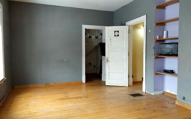 empty room featuring visible vents, baseboards, and light wood-type flooring