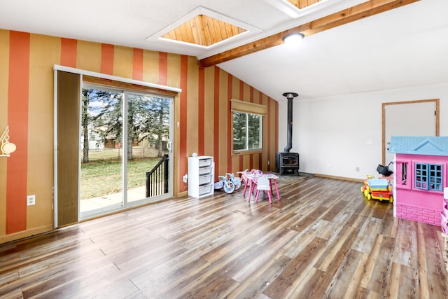 rec room with hardwood / wood-style flooring, a wood stove, and lofted ceiling with beams