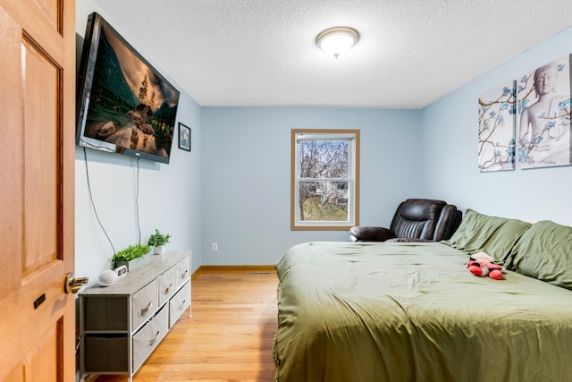 bedroom featuring a textured ceiling and light hardwood / wood-style floors