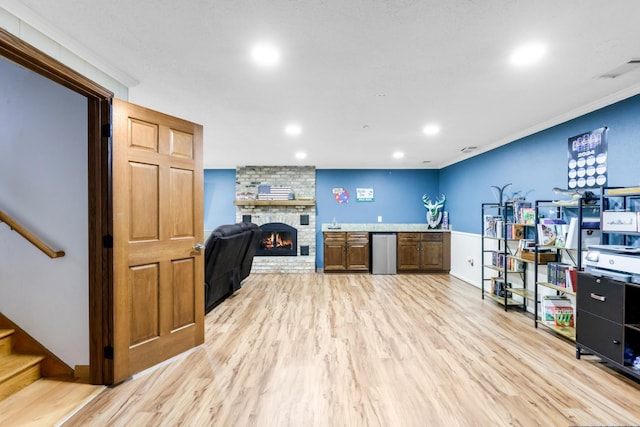 interior space featuring ornamental molding, refrigerator, a fireplace, and light hardwood / wood-style floors