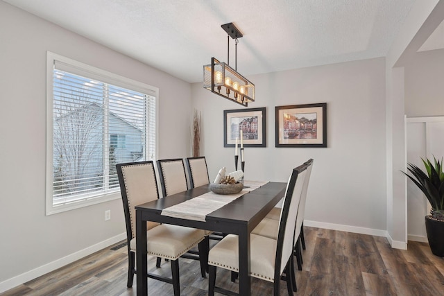 dining room with a textured ceiling, dark wood-type flooring, and a healthy amount of sunlight