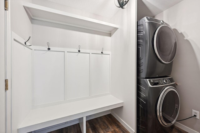 mudroom with a textured ceiling, stacked washer / dryer, and dark wood-type flooring