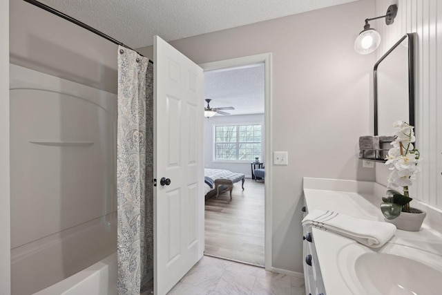 bathroom featuring vanity, hardwood / wood-style flooring, ceiling fan, shower / bath combo with shower curtain, and a textured ceiling