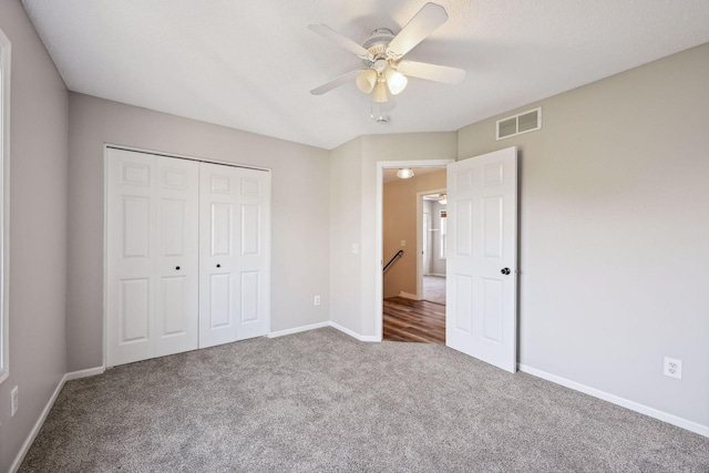 unfurnished bedroom featuring a textured ceiling, carpet floors, a closet, and ceiling fan