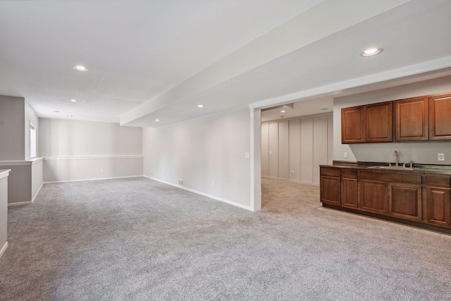 unfurnished living room featuring sink and light carpet