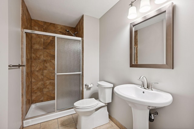 bathroom featuring tile patterned flooring, toilet, and a shower with shower door