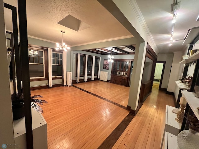 interior space with hardwood / wood-style flooring, a notable chandelier, radiator heating unit, and crown molding