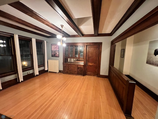 interior space featuring radiator heating unit, beamed ceiling, and light wood-type flooring