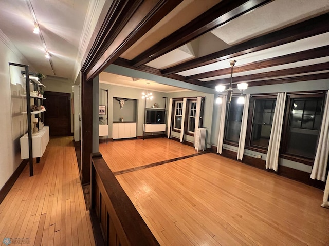 interior space with light wood-type flooring, radiator heating unit, rail lighting, and an inviting chandelier