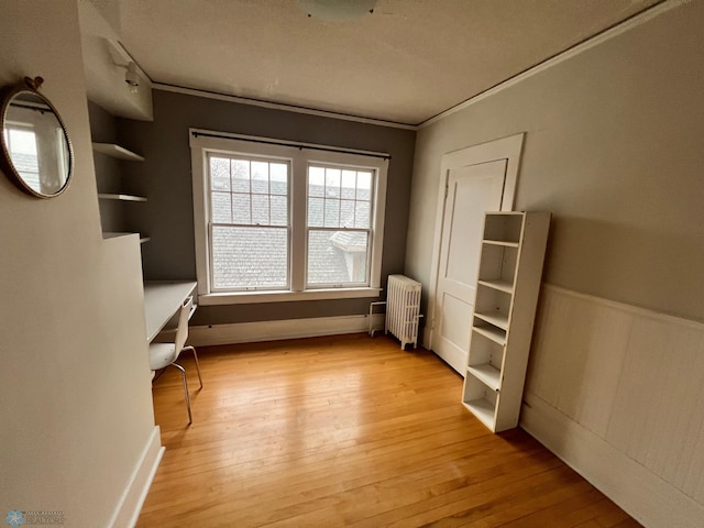 interior space featuring radiator heating unit, ornamental molding, and light wood-type flooring