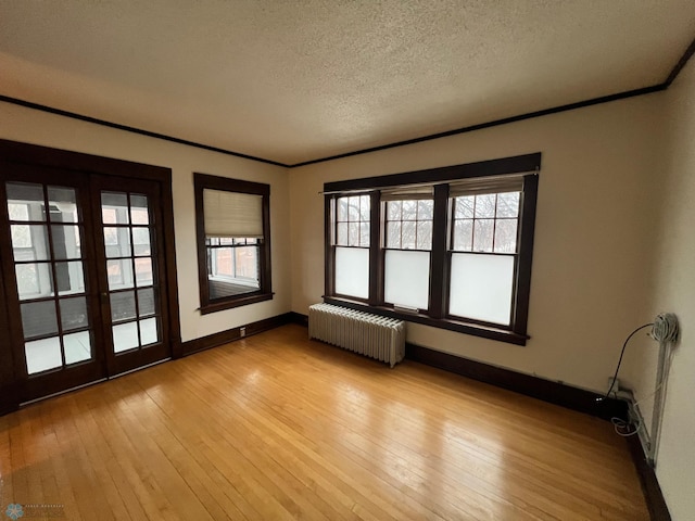 unfurnished room with a textured ceiling, light hardwood / wood-style flooring, and radiator