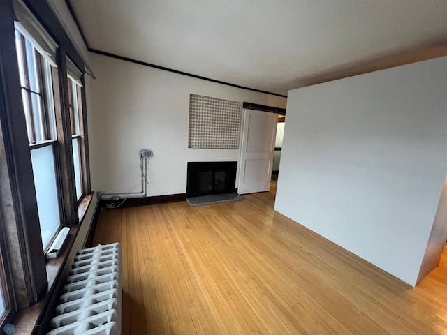 unfurnished living room with radiator heating unit and light wood-type flooring