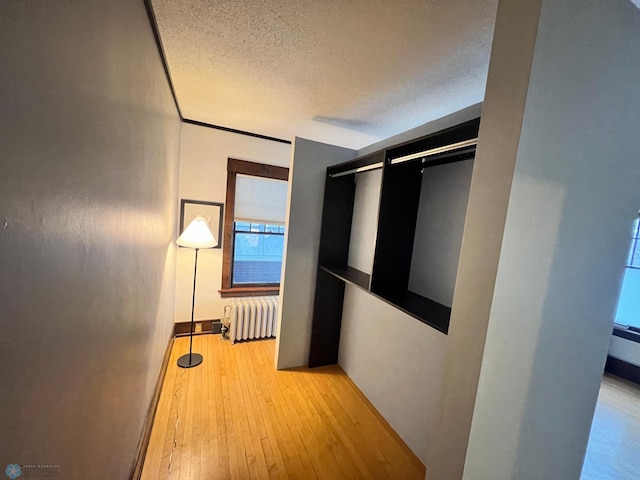 corridor featuring light hardwood / wood-style floors, a textured ceiling, and radiator